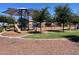 Community playground with a slide, climbing structures, and shade, surrounded by trees and mulch at 19771 W Woodlands Ave, Buckeye, AZ 85326