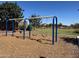 Community playground featuring swings in a well-maintained park, surrounded by green grass and trees at 19771 W Woodlands Ave, Buckeye, AZ 85326