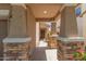 Covered porch with stone columns leads to the home's entrance, offering curb appeal and shelter at 19771 W Woodlands Ave, Buckeye, AZ 85326
