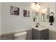 Cozy powder room features a pedestal sink with framed mirror, artwork, a white toilet and two-tone wall at 22610 W Mohave St, Buckeye, AZ 85326