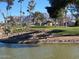 Scenic view of the golf course with a pond, mature trees, and mountain views at 2290 S Seminole Dr, Apache Junction, AZ 85119
