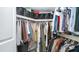 Well-organized walk-in closet with rods and shelves filled with clothes and storage bins at 2615 N Hayden Rd # 114, Scottsdale, AZ 85257