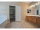 Bathroom featuring double sinks, tile flooring, and a walk-in closet at 30268 W Sheila Ln, Buckeye, AZ 85396