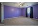 Bedroom with ceiling fan, neutral-colored carpeting and unique painted purple walls at 30268 W Sheila Ln, Buckeye, AZ 85396