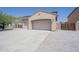 Exterior showcasing a wide driveway leading to a three-car garage, plus desert landscaping at 30268 W Sheila Ln, Buckeye, AZ 85396