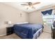 Neutral bedroom features a ceiling fan, bedside table with lamp and window with blue curtain at 3228 W Saint Anne Ave, Phoenix, AZ 85041