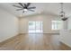 A spacious living room with wood-look floors, modern fan, pendant lighting, and slider door to the backyard at 3701 W Villa Maria Dr, Glendale, AZ 85308