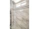Shower featuring elegant gray and white marble tile, a window, and modern shower fixtures at 3701 W Villa Maria Dr, Glendale, AZ 85308
