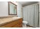 Well-lit bathroom featuring a vanity with a wood cabinet, granite countertop, and a shower with striped curtain at 6035 N 9Th Ave, Phoenix, AZ 85013