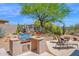 Outdoor kitchen with stainless steel grill, lounge chairs and desert landscaping under a clear sky at 7283 E Brisa Dr, Scottsdale, AZ 85266
