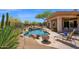 Backyard pool with rock waterfall, desert landscaping, lounge chairs and a covered patio at 7283 E Brisa Dr, Scottsdale, AZ 85266