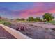 View of the backyard landscaping with desert vegetation, golf course, and homes under a gorgeous twilight sky at 8061 E Lavender Dr, Gold Canyon, AZ 85118