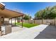 A covered patio overlooks a well-manicured lawn with a charming pergola and outdoor grill at 8343 W Paradise Dr, Peoria, AZ 85345