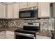 Modern kitchen features stainless steel appliances, mosaic backsplash, and light-colored cabinets at 8343 W Paradise Dr, Peoria, AZ 85345