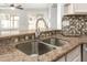 Close-up on a kitchen sink area with tiled backsplash and granite countertop at 8343 W Paradise Dr, Peoria, AZ 85345