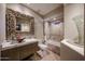 Bright bathroom featuring an ornate mirror, glass vessel sink, and a soaking tub at 8880 E Paraiso Dr # 120, Scottsdale, AZ 85255
