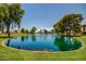 A serene pond with a fountain, surrounded by lush greenery and mature trees at 10124 E Michigan Ave, Sun Lakes, AZ 85248