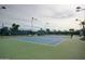 Outdoor tennis court featuring blue and green surface surrounded by net fencing and trees at 10124 E Michigan Ave, Sun Lakes, AZ 85248