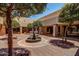 A decorative water fountain in a courtyard, surrounded by mature trees and pathways at 10124 E Michigan Ave, Sun Lakes, AZ 85248
