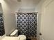 Bright bathroom featuring a toilet, shower with stylish black-and-white curtain, and a white door at 10347 W Odeum Ln, Tolleson, AZ 85353
