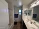 Bright bathroom featuring double sinks, shower over tub, tile floors, and neutral wall color at 10347 W Odeum Ln, Tolleson, AZ 85353