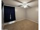 Bright, carpeted bedroom featuring a ceiling fan, and dark curtains blocking light from the window at 10347 W Odeum Ln, Tolleson, AZ 85353