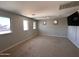 A spacious bonus room with carpet, three windows, and a wall mounted TV offers great flexible space at 10347 W Odeum Ln, Tolleson, AZ 85353