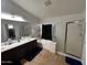 Bright main bathroom boasts double sinks, a shower over tub and tile flooring at 10347 W Odeum Ln, Tolleson, AZ 85353