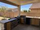 Covered patio featuring an outdoor kitchen with stone accents and a built-in grill and sink at 10347 W Odeum Ln, Tolleson, AZ 85353