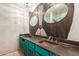 Bathroom featuring double sinks, a vanity with turquoise cabinets, and decorative mirrors at 1123 W Mendoza Ave, Mesa, AZ 85210
