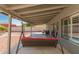 Spacious covered patio featuring a comfortable swing and view of the well-maintained backyard at 12325 W Dreyfus Dr, El Mirage, AZ 85335