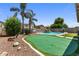 Lush backyard featuring a putting green, pool, rock landscaping, and mature shade trees and a basketball hoop at 1564 E Leaf Rd, San Tan Valley, AZ 85140