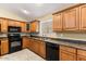 Well-lit kitchen with wooden cabinets, black appliances, and a functional layout, great for cooking and meal prep at 1564 E Leaf Rd, San Tan Valley, AZ 85140
