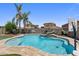 Sparkling pool features rock waterfall and sunbathing area plus desert landscaping, basketball hoop, and rock wall at 1564 E Leaf Rd, San Tan Valley, AZ 85140