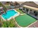 Aerial view of backyard featuring a sparkling pool, putting green, covered patio with grill, and manicured landscaping at 1564 E Leaf Rd, San Tan Valley, AZ 85140