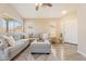 Comfortable living room featuring a neutral sectional, plush ottoman, and wood-look flooring at 16586 W Latham St, Goodyear, AZ 85338
