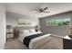 A staged carpeted bedroom with a ceiling fan, side tables, and a large bright window at 1747 W Devon --, Mesa, AZ 85201