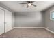 An empty carpeted bedroom with a ceiling fan, closet space, and bright natural light at 1747 W Devon --, Mesa, AZ 85201