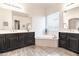 A bright primary bathroom features dual sinks, dark cabinets, and a stand alone soaking tub at 19598 E Walnut Rd, Queen Creek, AZ 85142