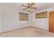 This is a carpeted bedroom with a ceiling fan and two windows with wood trim and blinds at 2138 W Northview Ave, Phoenix, AZ 85021