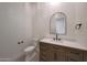 Stylish powder room with a wood vanity, white countertop, and arched mirror at 2859 E Los Altos Rd, Gilbert, AZ 85297