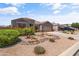 Inviting single-story home with a two-car garage, desert landscaping, and colorful flower bushes at 36130 N Quiros Dr, Queen Creek, AZ 85143