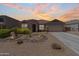 Charming single-story home featuring desert landscaping, a two-car garage, and a welcoming front porch with seating at 36130 N Quiros Dr, Queen Creek, AZ 85143