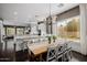 Open-concept dining area with a wooden table, white chairs, and access to the modern kitchen at 3955 E Fox Cir, Mesa, AZ 85205