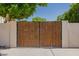 Wooden front gate in between two white columns with green trees behind at 3955 E Fox Cir, Mesa, AZ 85205