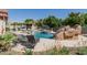 Resort-style backyard pool with rock features, lounge chairs, and an outdoor kitchen, perfect for entertaining and relaxation at 3955 E Fox Cir, Mesa, AZ 85205