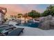 Backyard oasis featuring a sparkling pool, spa, rock waterfall, covered patio and lounge area at 3955 E Fox Cir, Mesa, AZ 85205