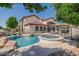 Inviting backyard pool and spa featuring rock accents, lounge chairs, and covered patio for relaxing and entertaining at 3955 E Fox Cir, Mesa, AZ 85205