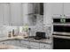 Close up of a gas stove top with decorative backsplash, stainless steel hood, and white cabinets at 3955 E Fox Cir, Mesa, AZ 85205