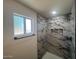 A bathroom featuring marble-look tiling in the shower and a window at 5951 W Granada Rd, Phoenix, AZ 85035